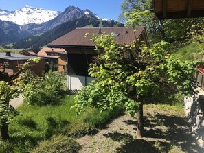 Ein Wohngebiet an einem Hang, mit einem Haus mit geneigtem Dach und Blick auf verschneite Berge im Hintergrund.