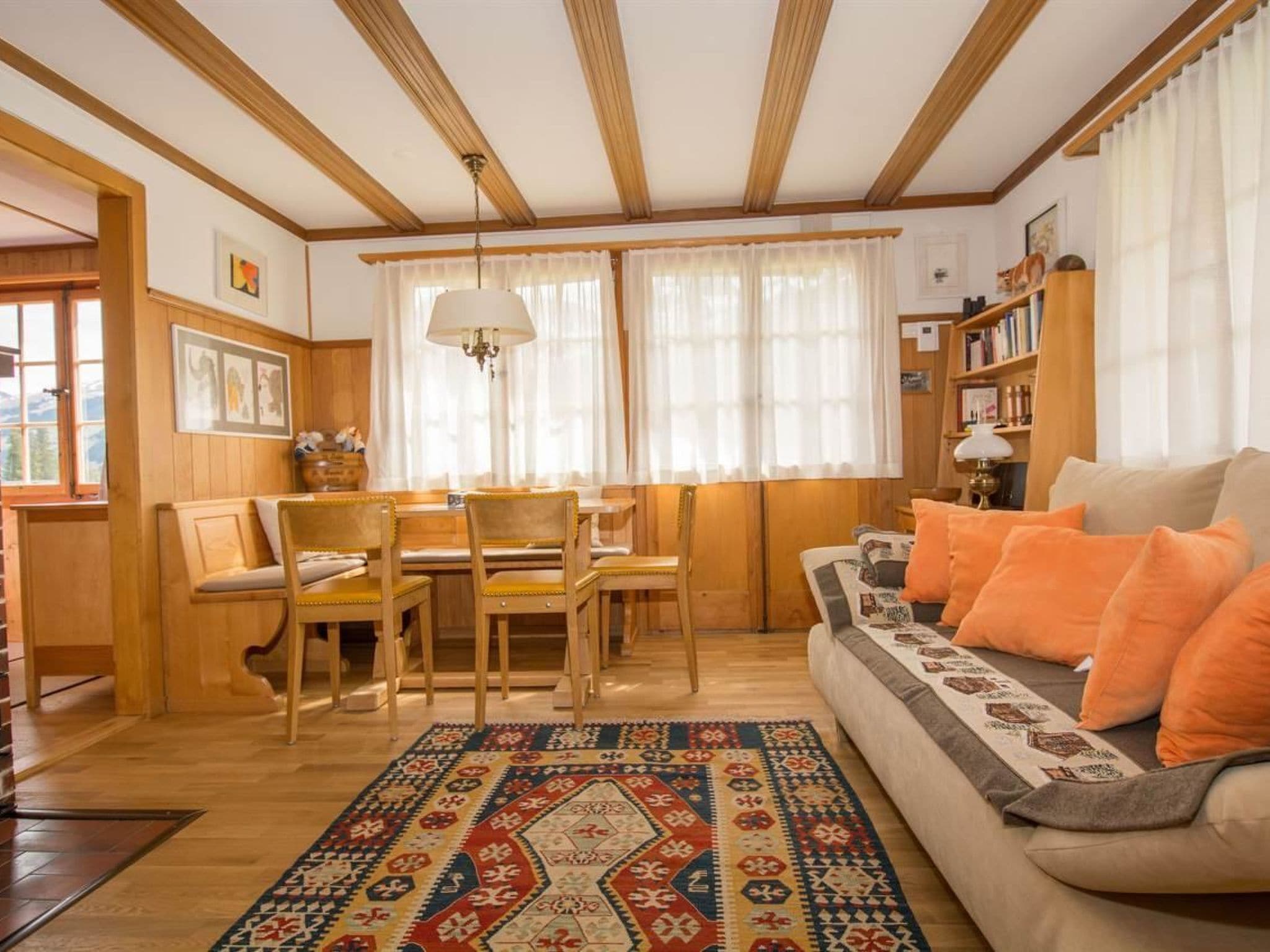 A cozy living room with a sofa, a rug, and a dining area with chairs and a table.