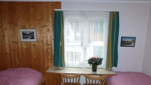 A room with two single beds, a wooden desk with chairs, a window with curtains, and two framed pictures on the walls. - Bärggeist, Gruebiweg 8, Adelboden Appartement/Fewo, Dusche und Bad, WC, 4 oder m by Interhome (Adelboden)