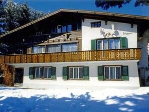 Ein zweistöckiges Gebäude mit Balkon, Holzgeländern und grünen Fensterläden.