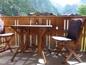 A wooden deck with a table and two chairs, overlooking a mountainous landscape. - Chalet Kanderblick Appartement/Fewo, Bad, WC, Balkon by Interhome (Kandersteg)