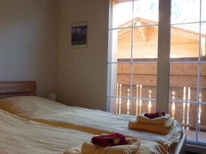 A room with a bed, a window with wooden shutters, and a small picture on the wall.
