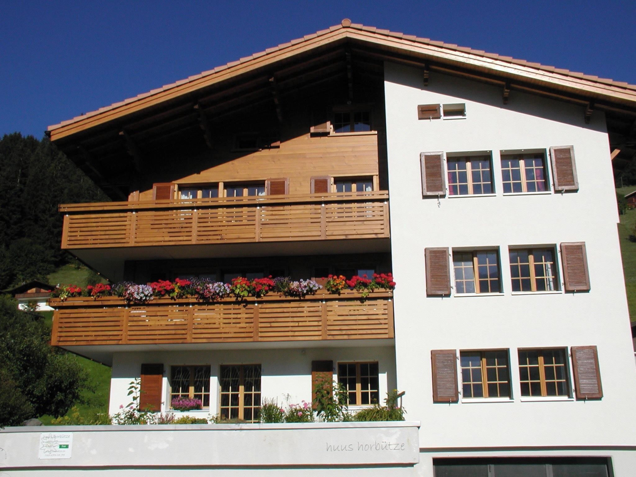 A two-story building with wooden balconies and flower boxes.