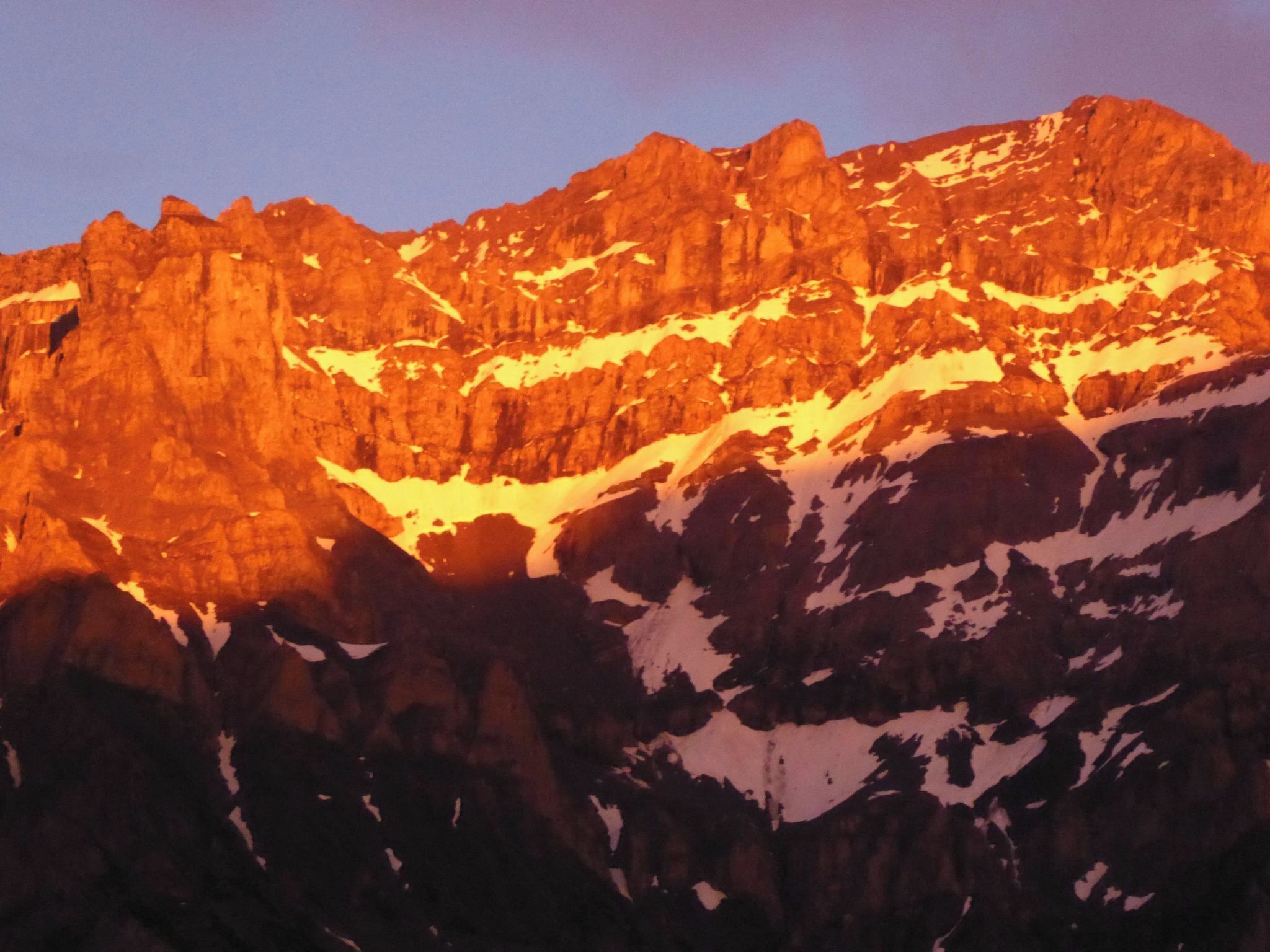 Un paysage montagneux caractérisé par un terrain rocheux et des zones recouvertes de neige.