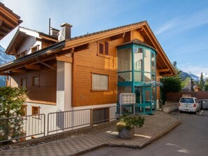 A wooden chalet with a glass entrance, a small parking area, and a mountain backdrop. - Loft Erlebnis Adelboden Appartement/Fewo, Dusche, WC, 2 Schlafräume by Interhome (Adelboden)