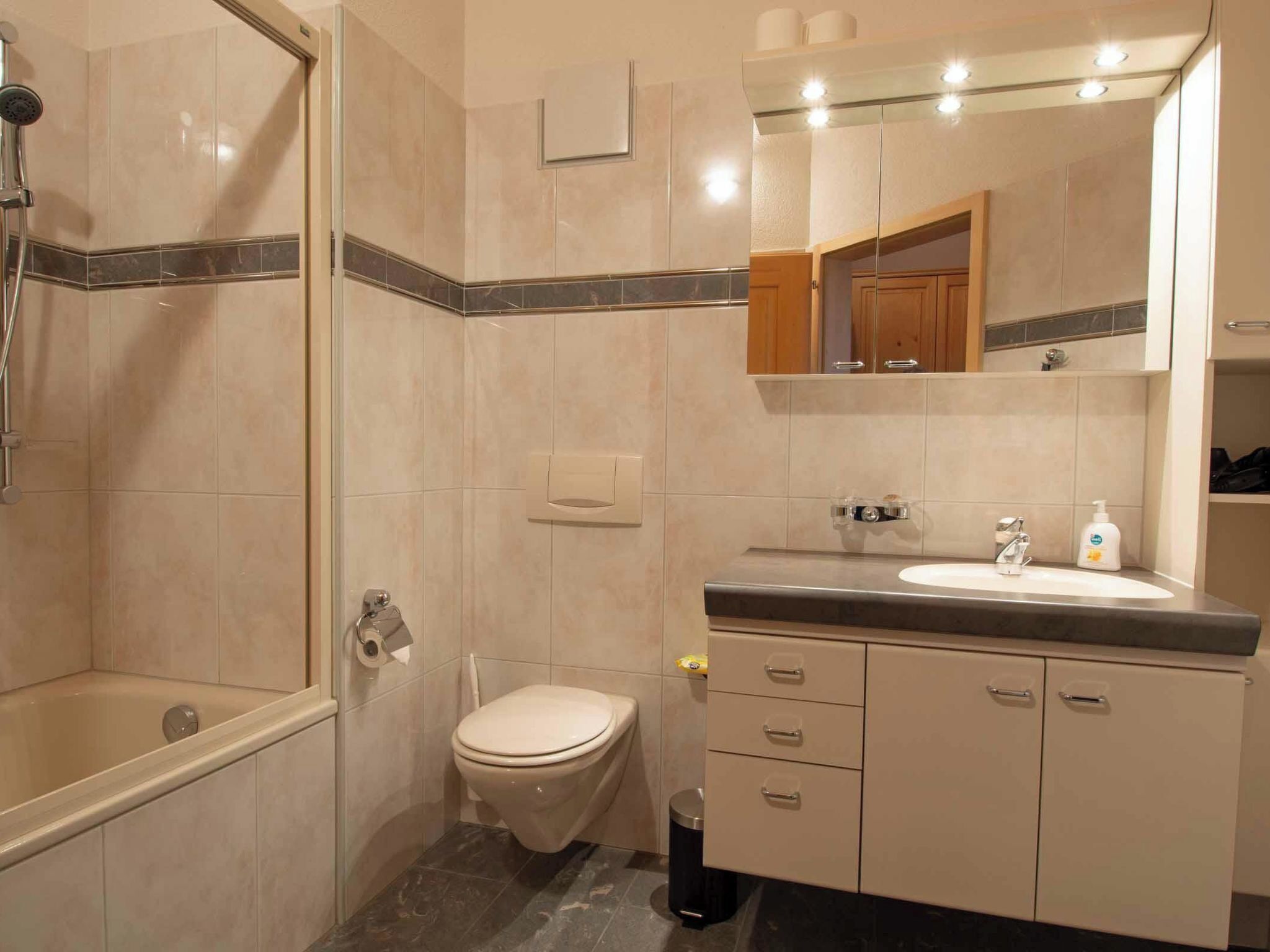 Een badkamer met douche, toilet, wastafel en wastafelmeubel.