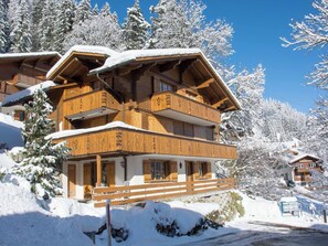 A multi-story wooden chalet with balconies, surrounded by snow-covered trees. - Senggi Appartement/Fewo, Dusche, WC, 1 Schlafraum 2-Zimmerwohnung by Interhome (Adelboden)
