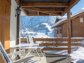 A wooden outdoor seating area with a table and chairs, overlooking a snowy mountain landscape. - Senggi Appartement/Fewo, Dusche, WC, 1 Schlafraum 2-Zimmerwohnung by Interhome (Adelboden)