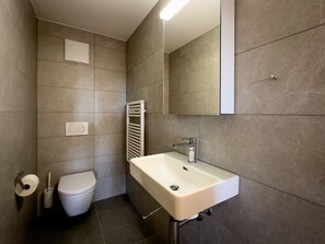 A modern bathroom with a white sink, a toilet, and a towel rack. - Ferienwohnung Lohner (EG) Appartement/Fewo, Dusche, WC, 3 Schlafräume by Interhome (Adelboden)