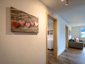 Ein Flur mit einer Holzwanddekoration, einem grauen Sofa und einem Fenster mit Blick.