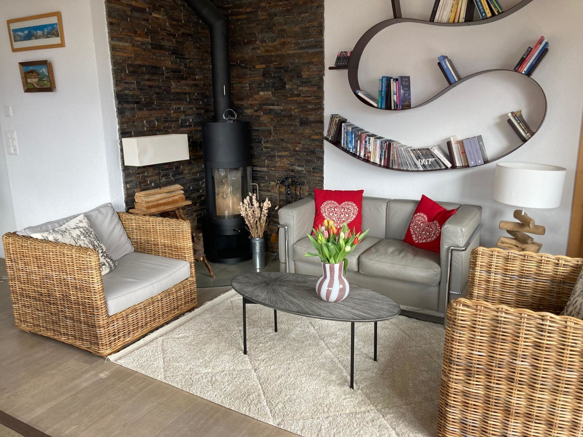 Uma sala de estar aconchegante com lareira, móveis de vime, uma mesa de centro e uma estante de livros.