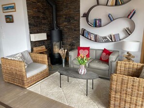 A cozy living room with a fireplace, wicker furniture, a coffee table, and a bookshelf. - Gartenweg Appartement/Fewo, Dusche und Bad, WC, 4 oder mehr Schlafräume by Interhome (Adelboden)