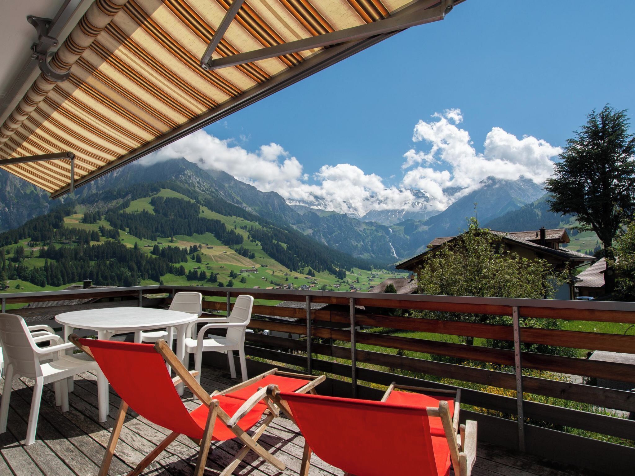 Eine Terrasse mit Blick auf Berge, einem Tisch und Stühlen.