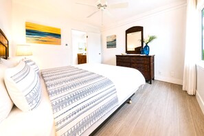 Ein Schlafzimmer mit einem Bett, einem Schminktisch, einem Spiegel und einem Deckenventilator.