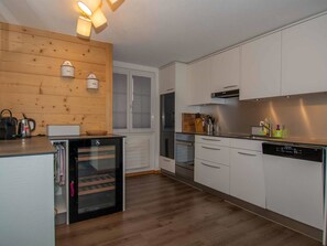 Une cuisine moderne avec des meubles blancs, un four encastré et un lave-vaisselle.