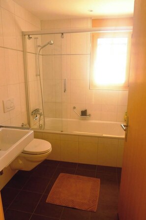 A bathroom with a glass-enclosed shower, a bathtub, a toilet, and a sink. - Mühleport Appartement/Fewo, Bad, WC, 1 Schlafraum 2.5-Zimmerwohnung by Interhome (Adelboden)