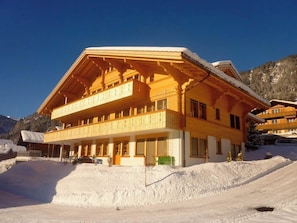 Een meerlaags houten gebouw met balkons, gelegen in een besneeuwd berglandschap.