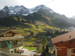 A mountain landscape with snow-capped peaks, a valley with scattered houses, and a building with a balcony overlooking the view. - Mühleport Appartement/Fewo, Bad, WC, 1 Schlafraum 2.5-Zimmerwohnung by Interhome (Adelboden)