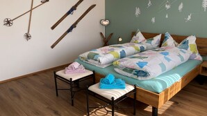 Un dormitorio con cama, una silla, un perchero para esquíes en la pared y una pared con un mural de temática natural.