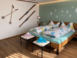 Ein Schlafzimmer mit Bett, einem Sessel, einem an der Wand befestigten Skiregal und einer Wand mit einem Wandgemälde zum Thema Natur.