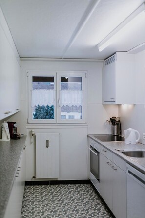 A compact kitchen with a window, a built-in oven, and a sink. - Aloa Appartement/Fewo, Bad, WC, 2 Schlafräume 3.5-Zimmerwohnung by Interhome (Adelboden)