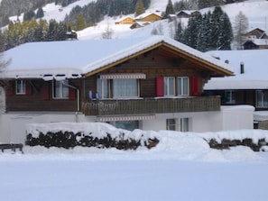 Eine Holzhütte mit Balkon, eingebettet in eine verschneite Landschaft mit Bäumen.