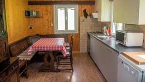 A kitchen with a wooden table, chairs, a microwave, and a sink. - Chalet Bondertal Appartement/Fewo, Dusche, WC, 2 Schlafräume 3.5-Zimmerwohnung by Interhome (Adelboden)