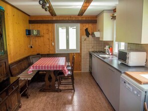 Eine Küche mit einem Holztisch, Stühlen, einer Mikrowelle und einem Spülbecken.