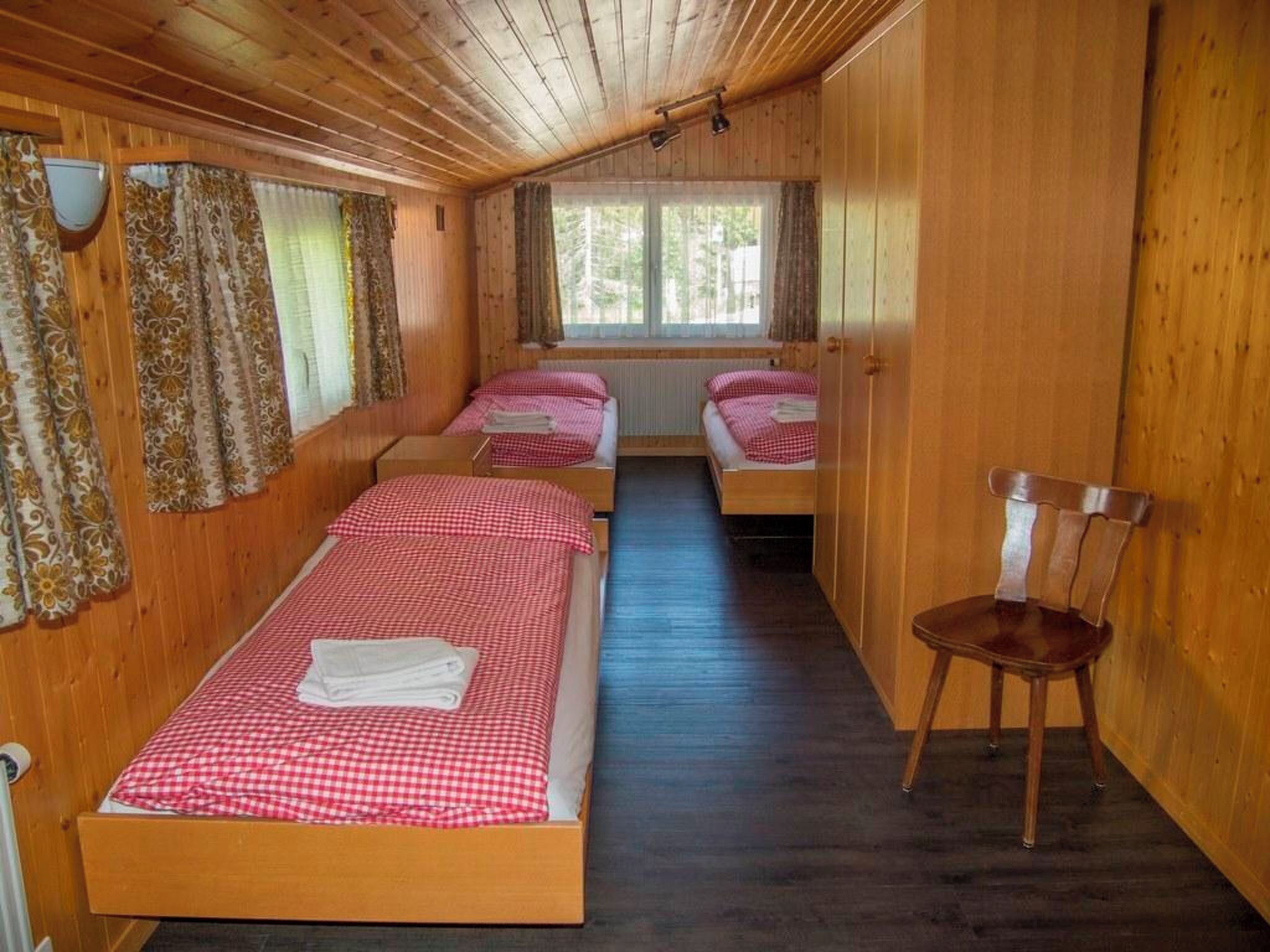 A cabin with two beds, a chair, and a window.