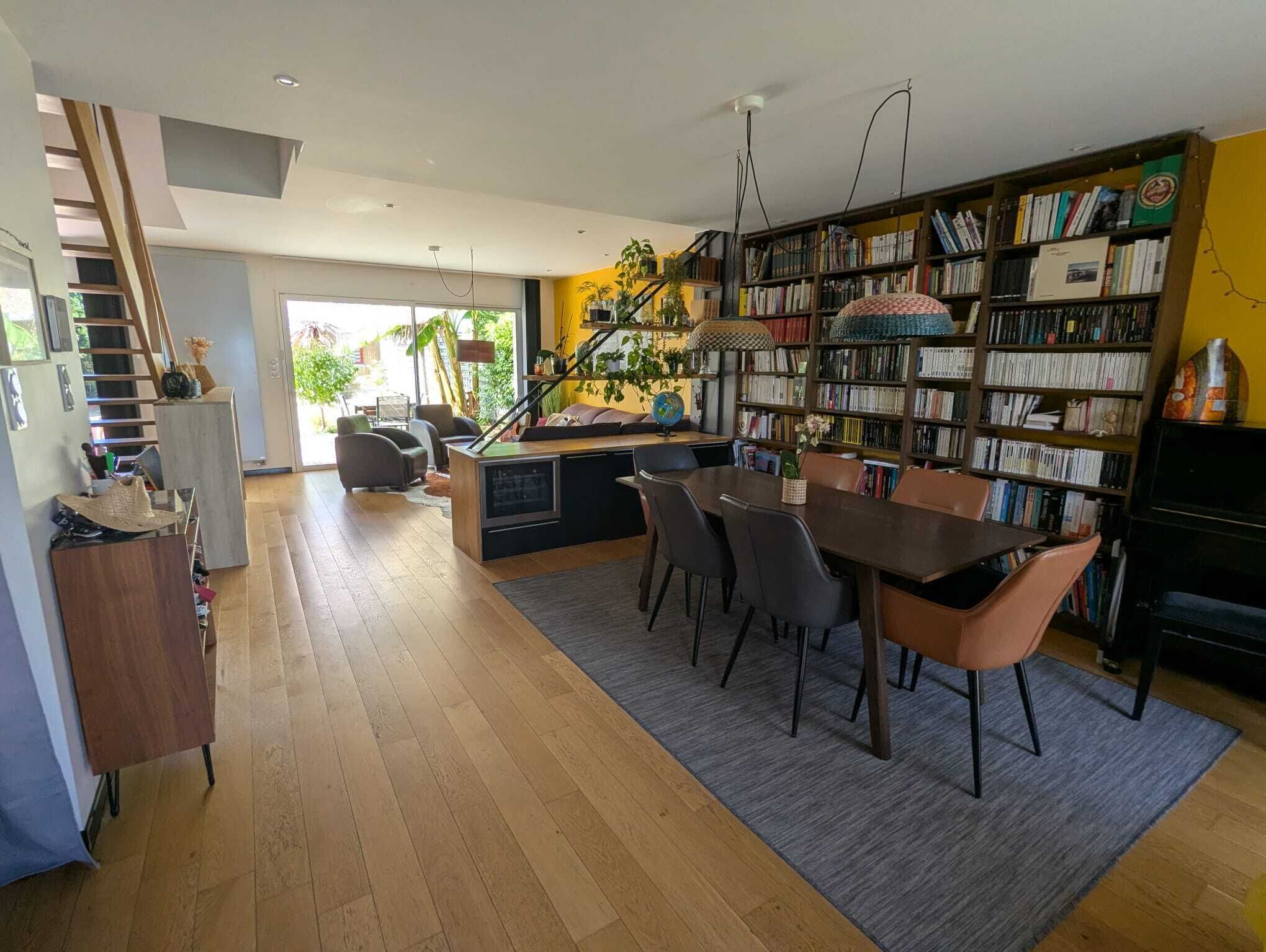Ein moderner Wohnbereich mit Essbereich, Küche und einem großen Bücherregal voller Bücher.