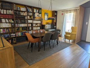 Ein Essbereich mit einem Holztisch und Stühlen, umgeben von Bücherregalen voller Bücher.