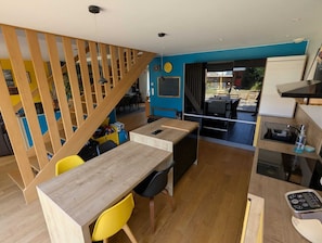 Eine moderne Küche mit einer Holztreppe, einem Essbereich mit Tisch und Stühlen sowie Blick ins Freie.