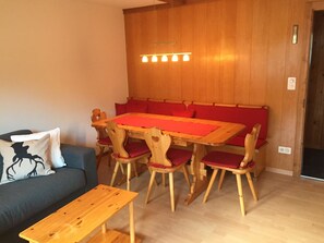 Ein Essbereich mit Holztisch und -stühlen, einer Couch und einer hölzernen Bank.
