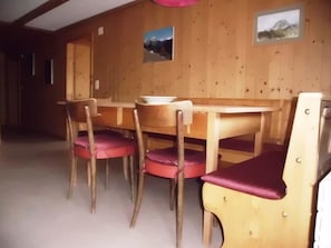 Ein Essbereich mit Holztisch und -stühlen, einem Fenster und zwei gerahmten Bildern an der Wand.