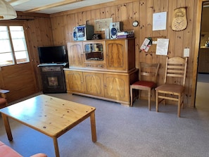 Ein Zimmer mit Holzvertäfelung, einem Fernseher, Holzschränken, einem kleinen Tisch und einem Stuhl.