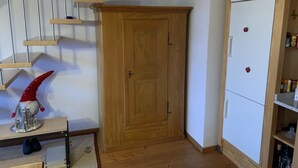 A wooden wardrobe, a white refrigerator, and a staircase with wooden steps. - Gartenstudio "Belle Vue" Appartement/Fewo, Bad, WC, 1 Schlafraum by Interhome (Frutigen)