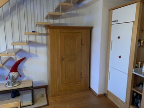 A wooden wardrobe, a white refrigerator, and a staircase with wooden steps. - Gartenstudio "Belle Vue" Appartement/Fewo, Bad, WC, 1 Schlafraum by Interhome (Frutigen)