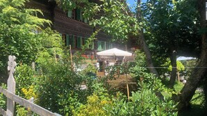 A traditional wooden building with a balcony, surrounded by lush greenery and a wooden fence. - Gartenstudio "Belle Vue" Appartement/Fewo, Bad, WC, 1 Schlafraum by Interhome (Frutigen)