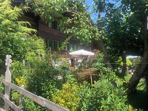 A traditional wooden building with a balcony, surrounded by lush greenery and a wooden fence. - Gartenstudio "Belle Vue" Appartement/Fewo, Bad, WC, 1 Schlafraum by Interhome (Frutigen)