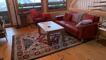 Un salon avec un canapé en cuir rouge, une table basse blanche et un tapis à motifs.