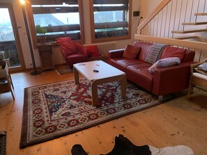 A living room with a red leather sofa, a white coffee table, and a patterned rug. - Gartenstudio "Belle Vue" Appartement/Fewo, Bad, WC, 1 Schlafraum by Interhome (Frutigen)