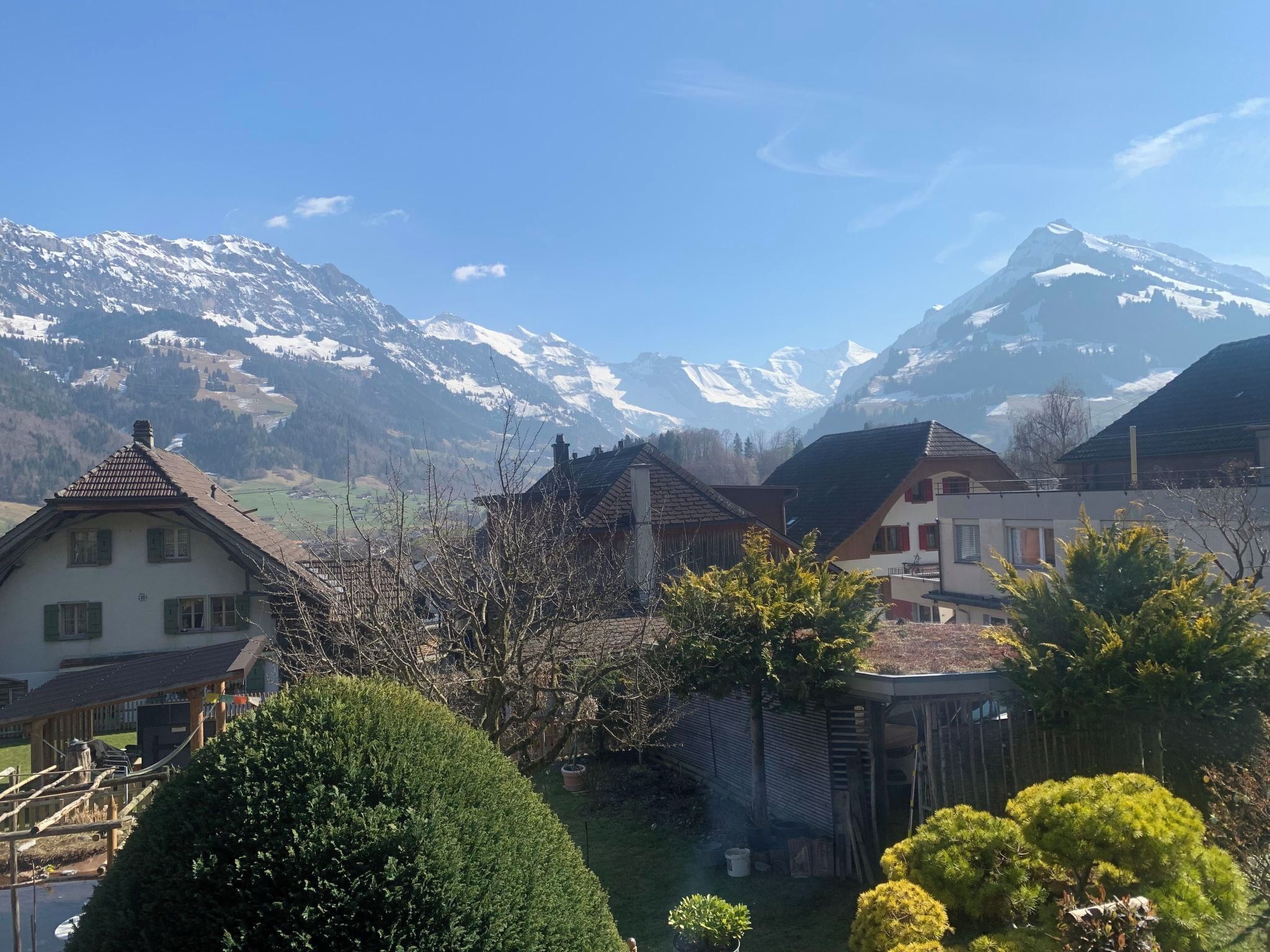 Ein Wohngebiet mit Häusern, einem Holzzaun und einer Bergkulisse im Hintergrund.