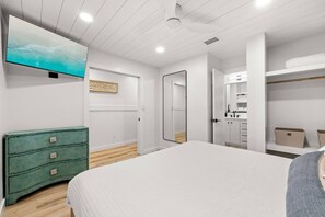 Un dormitorio moderno con una cama grande, un aparador verde, un cuadro en la pared y un vestidor.