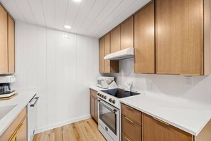 A kitchen with white cabinets, a microwave, a stove, and a wooden countertop. - Beach View.  Steps 2 Sand.  Remodel '26.  Sleeps 6 (Miramar Beach)