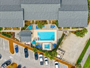 An aerial view of a hotel with a swimming pool, parking lot, and surrounding greenery. - Beach View.  Steps 2 Sand.  Remodel '26.  Sleeps 6 (Miramar Beach)
