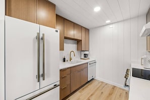 Une cuisine moderne avec des meubles blancs, un plan de travail en bois et un lave-vaisselle encastré.
