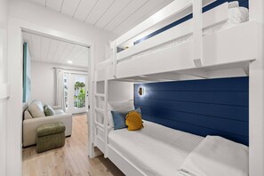 A bunk bed room with a white and blue color scheme, a sofa, and a view of the outdoors. - Beach View.  Steps 2 Sand.  Remodel '26.  Sleeps 6 (Miramar Beach)