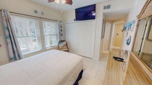 A bedroom with a bed, a wardrobe, a television displaying 'LIVE NEWS', and a window with blinds. - Poolside Ground Floor Sandpiper Cove 9135 (Destin)