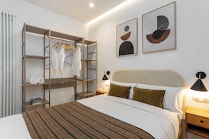 A hotel room with a bed, a wardrobe, a nightstand, and two wall-mounted lamps. - Discover this cozy one-bedroom apartment on Calle Blasco de Garay, in the heart of the Chamberí district, one of Madrid's most authentic and traditional neighborhoods. (MADRID)