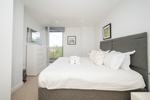 A modern bedroom with a large bed, a dresser, and a balcony view. - Comfortable 2BR apartment Deptford Yard, SE8 London - Pass the Keys (London)